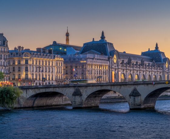 Blick auf die Seine mit Brücke, dem Musée d’Orsay und im Hintergrund dem Eiffelturm bei Sonnenuntergang in Paris.