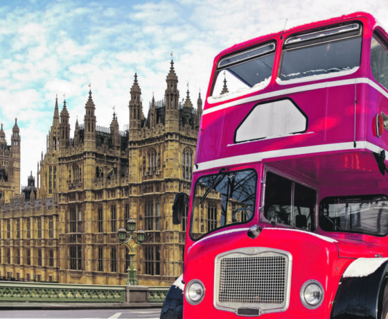 Roter Doppeldeckerbus in London vor dem Palace of Westminster und dem Uhrturm Big Ben bei blauem Himmel mit Wolken.